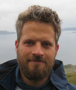 Portraitaufnahme von Benedikt Pontzen mit Vollbart und kurzem lockigen Kopfhaar